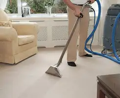 Carpet cleaning professional removing dirt and stains with a hot-water extraction tool in a home, Bakersfield, CA.